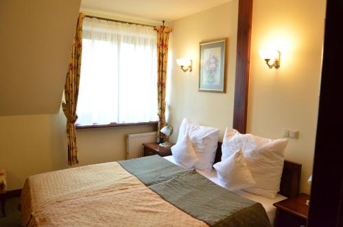 a bedroom with a bed with white pillows and a window at Hotel Villa Bohema in Kazimierz Dolny