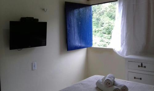 ein Schlafzimmer mit einem Handtuch auf einem Bett mit einem Fenster in der Unterkunft Pousada Vaca Brava in Areia