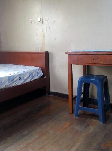 a room with a desk and a stool next to a bed at Anurak Guesthouse in Bangkok