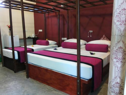 2 camas en una habitación de color púrpura y blanco en Sira's Chalets en Mirissa