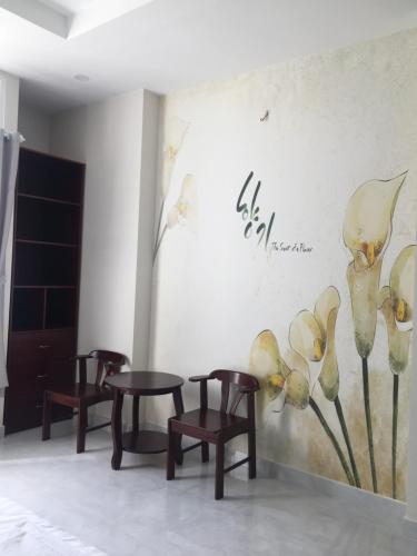 a room with three chairs and a wall with flowers at Phong Lan Guesthouse in Chau Doc