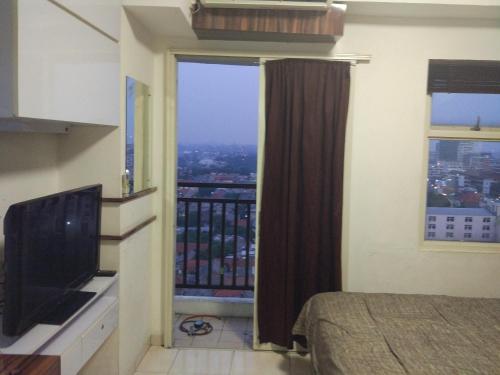 a bedroom with a large window and a television at DSV Margonda Residen 2 Apartment in Depok