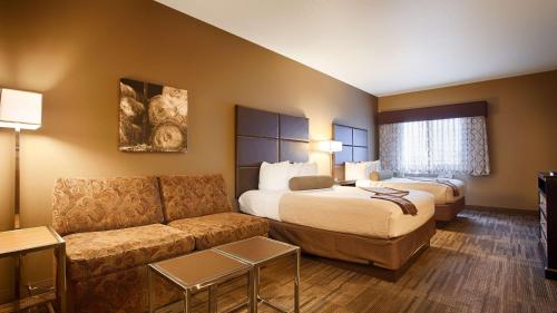 une chambre d'hôtel avec un lit et un canapé dans l'établissement Best Western Plus Night Watchman Inn & Suites, à Greensburg