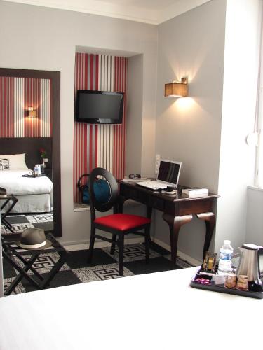 a room with a desk with a laptop and a bed at Logis Hotel - Le Charleston in Le Mans