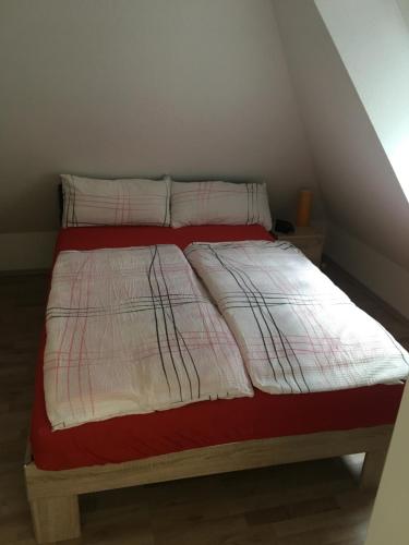 ein Bett mit einer rot-weißen Decke und Kissen in der Unterkunft Formella in Eisenach