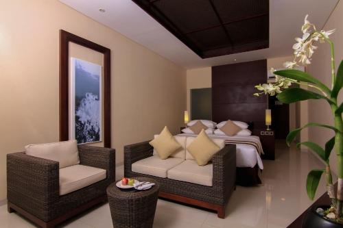 a bedroom with a bed and wicker chairs at Grand Luley Manado in Manado