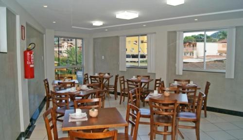 um restaurante com mesas e cadeiras de madeira e janelas em Caravelle Hotel em Guanhães