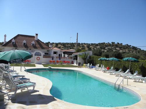 una gran piscina con sillas y sombrillas en Hotel Jardim, en Elvas