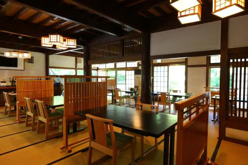 a dining room with tables and chairs and windows at Nukumorino-yado Komanoyu in Kiso