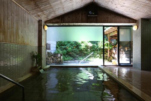 a swimming pool in a house with a water fountain at Nukumorino-yado Komanoyu in Kiso