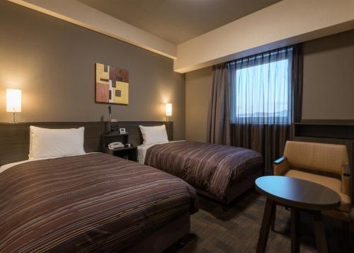 Pokój hotelowy z 2 łóżkami i krzesłem w obiekcie Hotel Route Inn Grand Kitami Ekimae w mieście Kitami
