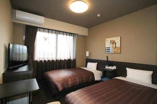 名取市Hotel Route-Inn Natori Iwanuma Inter -Sendai Kuko-的一间有两张床和一台平板电视的酒店房间