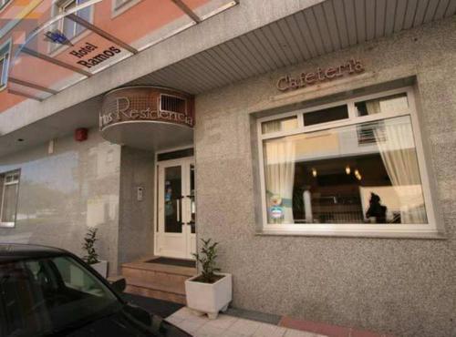 a building with a car parked outside of a restaurant at Hotel Ramos in Silleda