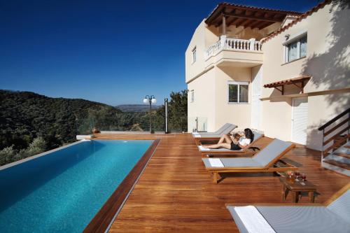 une femme assise sur des chaises longues à côté d'une piscine dans l'établissement Villa Drakona, à Keramia