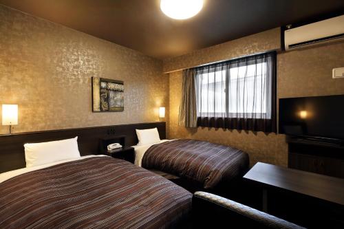 a hotel room with two beds and a television at Hotel Route Inn Ise in Ise