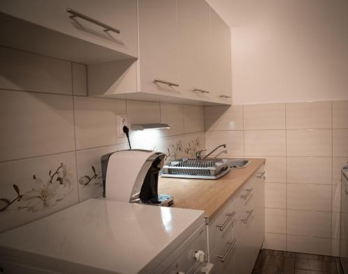 a white kitchen with a sink and a counter at Anna Apartman in Győr