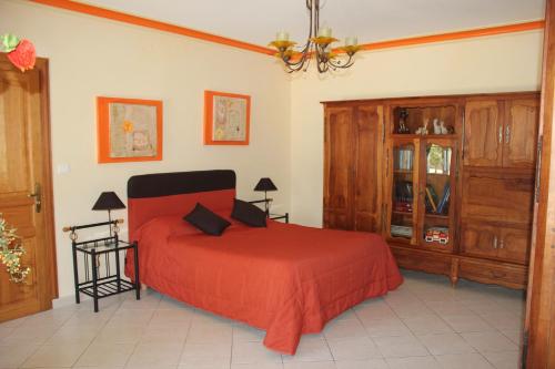 1 dormitorio con cama roja y armarios de madera en La Demeure de Bayard en Montagne