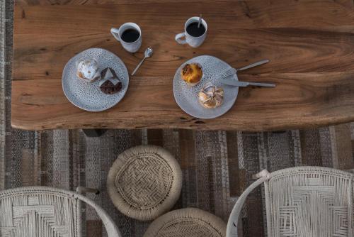a wooden table with two plates of food and cups of coffee at White & Co Exclusive Island Villas in Pirgos