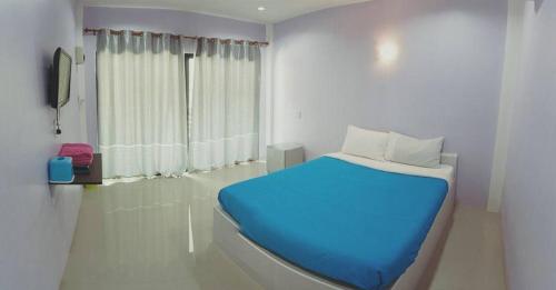 Un dormitorio con una cama azul y una ventana en Nam Sai Loft Resort, en Chao Lao Beach