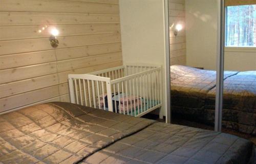 a bedroom with two twin beds and a crib at Kullasmarina Holiday Villas in Padasjoki