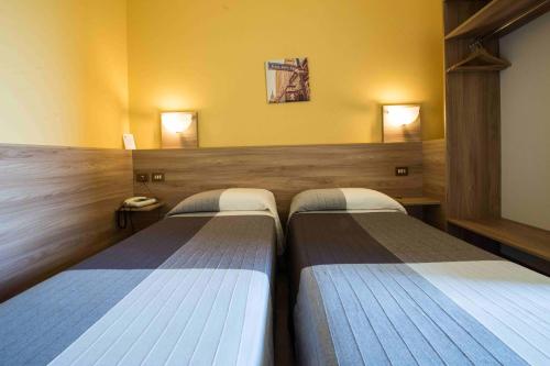 two beds in a room with yellow walls at Hotel Route 9 in Cadeo