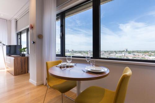 a dining room with a table and chairs and a large window at PREMIER SUITES PLUS Rotterdam in Rotterdam