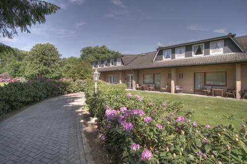 a house with a pathway leading to a yard with flowers at Jeddinger Hof Land- und Seminarhotel in Visselhövede