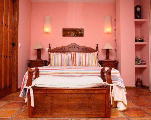 ギサンドにあるCasa Rural Samuel Paracaのピンクの壁のベッドルーム1室(大型ベッド1台付)