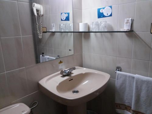 a bathroom with a sink and a toilet and a mirror at Hotel Avenida in Gijón