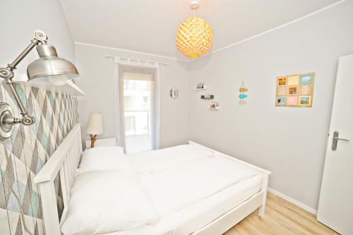 a white bedroom with a bed and a lamp at Bursztynowa Apartments by Grand Apartments in Gdańsk