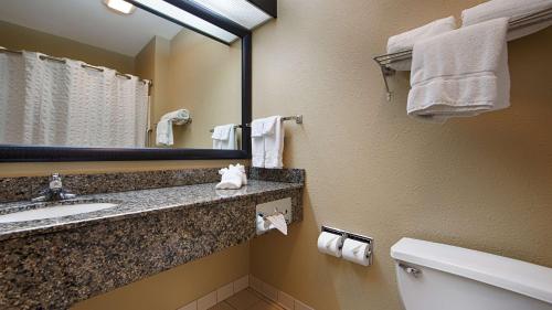 a bathroom with a sink and a mirror and a toilet at Best Western Macomb Inn in Macomb