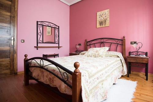 a bedroom with a bed with pink walls and a mirror at Maria la Carbayeda in Luanco