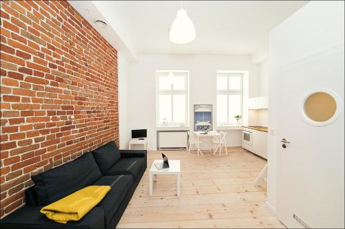 a living room with a black couch and a brick wall at Terra Studio Dworcowa in Wrocław