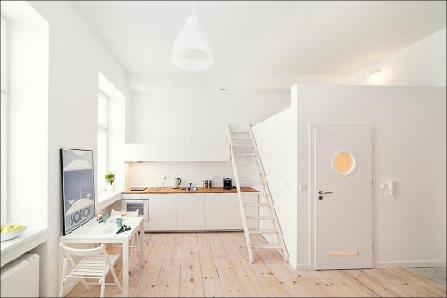 a white kitchen with a ladder next to a desk at Terra Studio Dworcowa in Wrocław