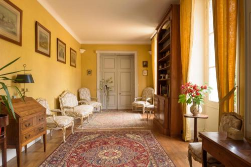 a living room with yellow walls and chairs and a door at Le Rossay in Saint-Clément-de-la-Place