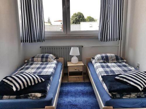 two beds in a room with two windows at Apartament Maryla in Giżycko