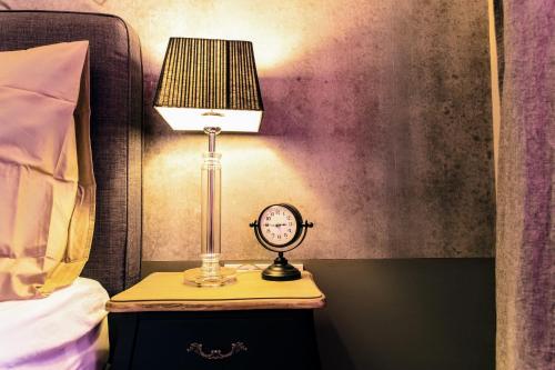 a lamp and a clock on a night stand next to a bed at SummerStreetSeven in Budapest