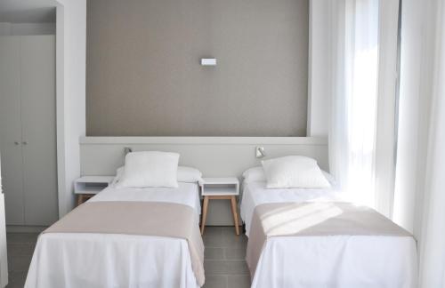 three beds in a room with white walls at Residencia Universitaria Tarragona Mediterrani in Tarragona