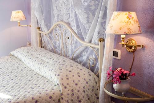 a bedroom with a white bed with a lamp and flowers at B&B Del Tempo Stretto in Albenga