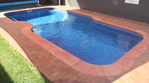 a swimming pool in a yard with a brick floor at The Saltbush Motor Inn in Hay