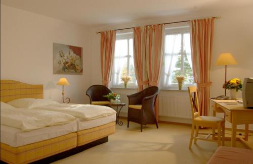 a bedroom with a bed and a desk and chairs at Bärenkrug in Molfsee