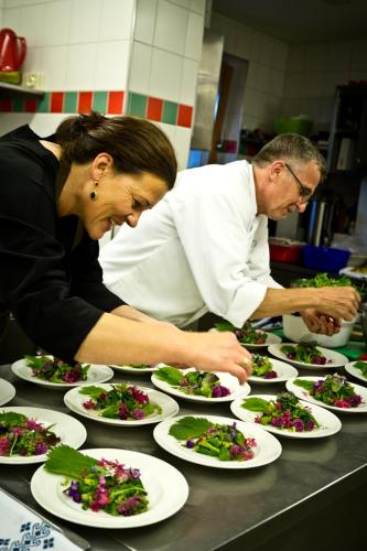two people in a kitchen preparing plates of food at Almhof Roswitha in Hippach