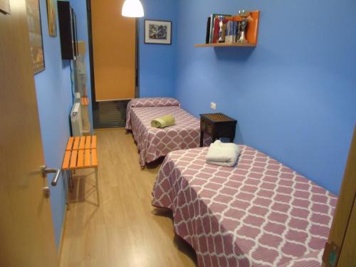 two beds in a room with blue walls at Apartamentos Mequedo in Alcañiz