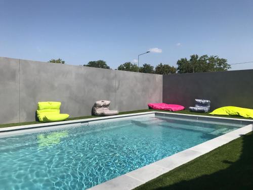 una piscina con sillas junto a una pared en Kyriad Direct Agen, en Castelculier