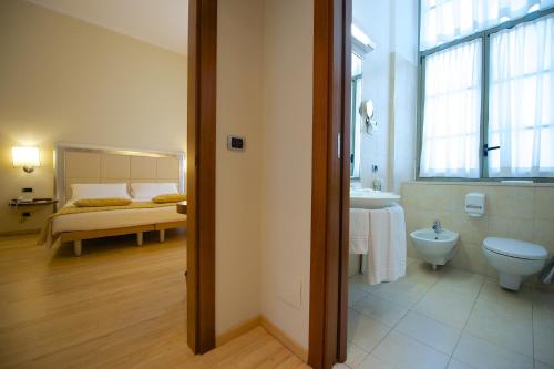 a bathroom with a toilet and a sink and a bed at Best Western Crystal Palace Hotel in Turin