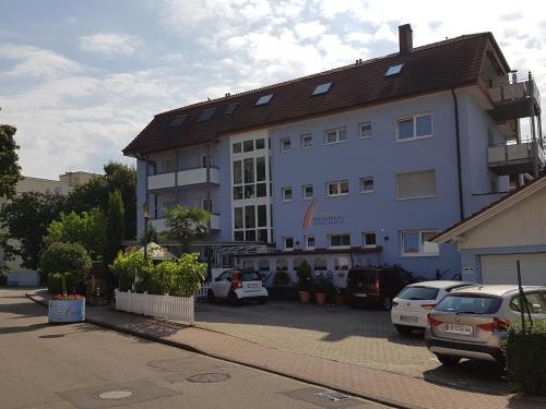 a large white building with cars parked in a parking lot at Regenbogen-Appartement in Bad Krozingen