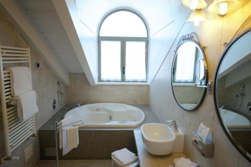W łazience znajduje się wanna, umywalka i lustro. w obiekcie Best Western Crystal Palace Hotel w Turynie