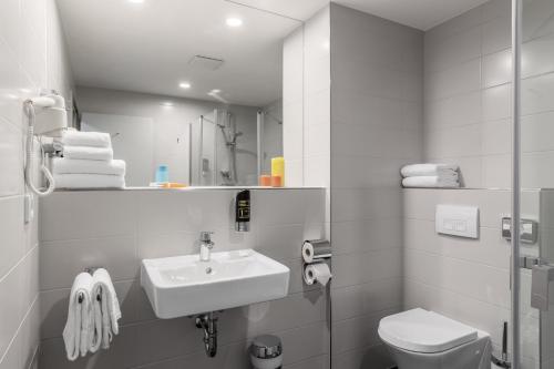 ein weißes Bad mit einem Waschbecken und einem WC in der Unterkunft Serways Hotel Steigerwald in Wachenroth