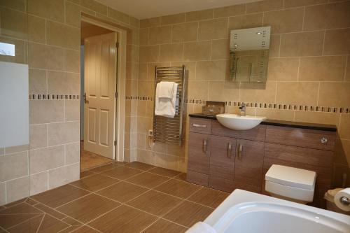 a bathroom with a sink, toilet and bathtub at Hundith Hill Hotel in Cockermouth