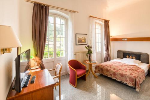 Schlafzimmer mit einem Bett, einem TV und einem Schreibtisch in der Unterkunft Grandhotel Esplanade in Bad Nenndorf